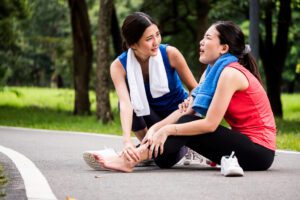 2 orang wanita sedang olahraga dan kaki temannya cedera